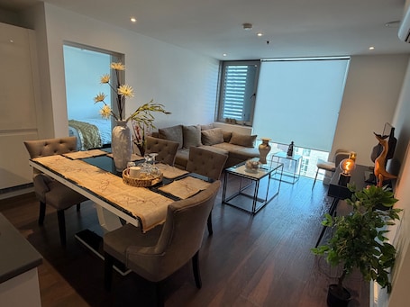 A modern living room with a sofa, a dining table with chairs, a coffee table, and a decorative vase.