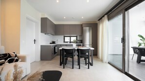 Eine moderne Küche mit Essbereich, einer Couch und einer Glastür, die auf einen Balkon führt.