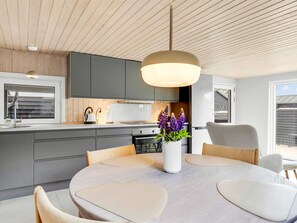 A modern kitchen with grey cabinets, a central island, and a dining area with a round table and chairs. - "Sylvelin" - 40m from the sea by Interhome (Sjølund)