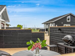 A patio with a round table, a grill, and a flower vase. - "Sylvelin" - 40m from the sea by Interhome (Sjølund)