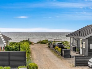 A coastal property with a gravel driveway leading to a beach, a parked car, and a house with a dark exterior. - "Sylvelin" - 40m from the sea by Interhome (Sjølund)