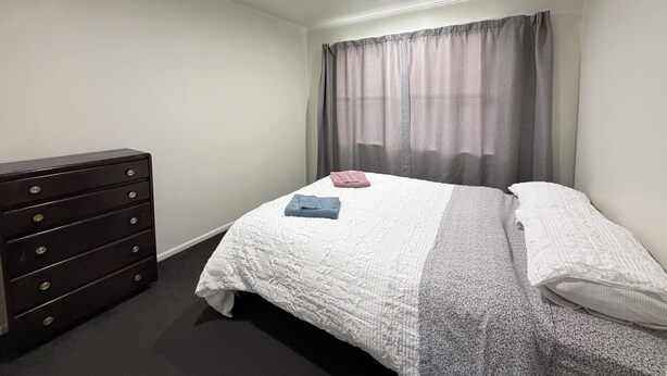 Une chambre à coucher avec un lit, une commode et une fenêtre avec des rideaux.