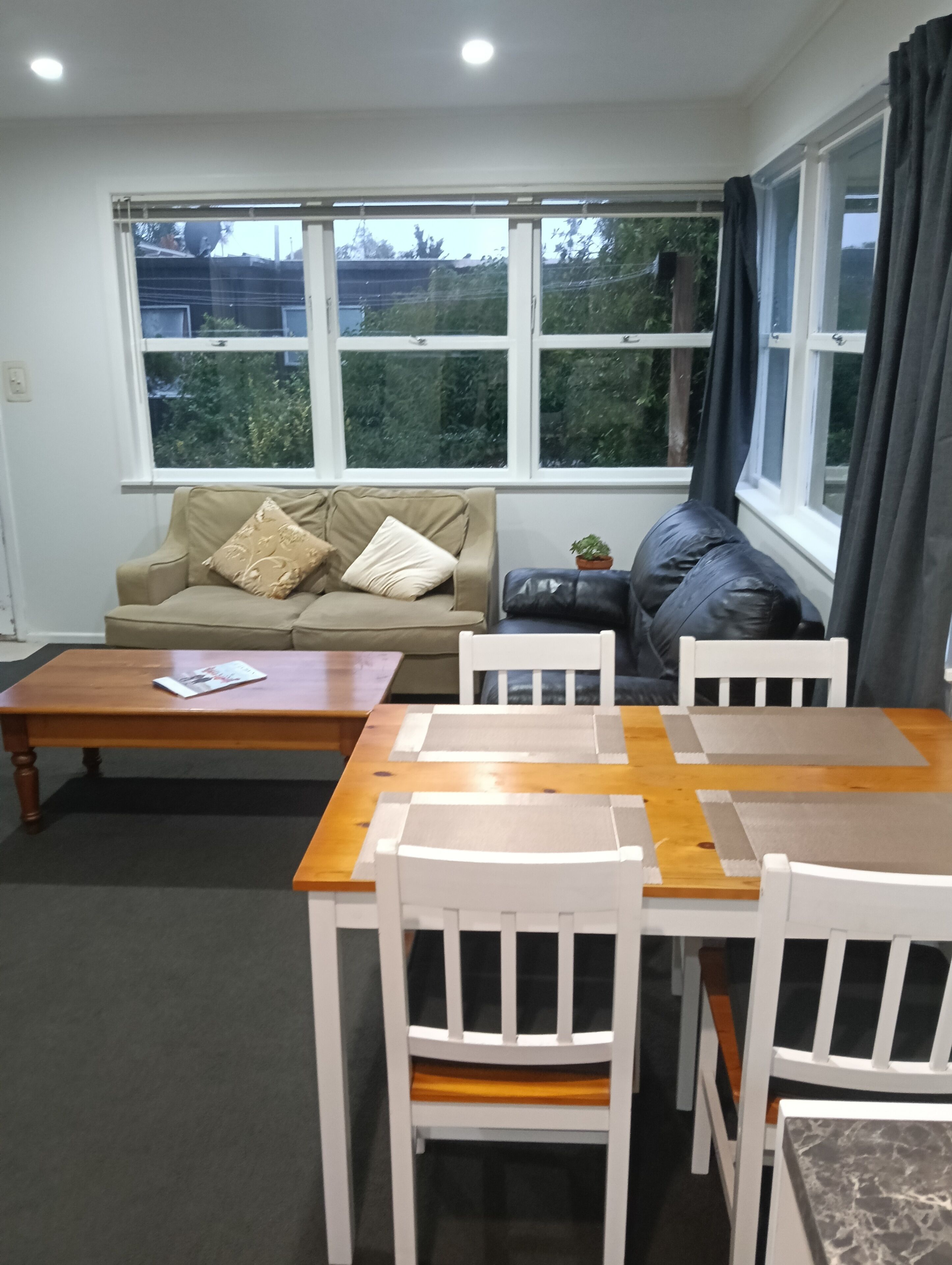 Een woonkamer met een bank, een salontafel en een eettafel met stoelen.