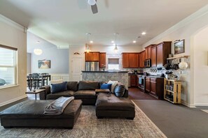 A modern kitchen with wooden cabinets, a built-in island, stainless steel appliances, and pendant lighting.