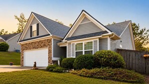 A two-story house with a garage, stone facade, and a well-maintained lawn.