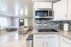 Una cocina moderna con armarios blancos, un microondas de acero inoxidable y una encimera de granito.