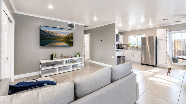 A modern living room with a grey sofa, a white entertainment unit, and a large landscape painting.