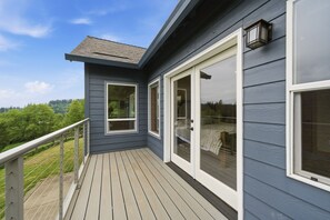 A deck with a railing, a sliding glass door, and a window. - Washougal 4BR - Hot Tub, Sauna, Private 5 Acres (Washougal)
