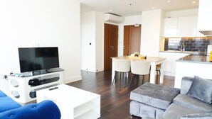 A modern living room with a TV, sofa, and dining area. - City Oasismodern London Apartment (London)