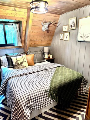 Ein Schlafzimmer mit einem Bett, Holzboden, einem Fenster und Bildern an der Wand.
