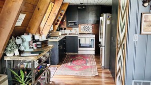 Una cocina con vigas de madera, microondas, estufa y refrigerador.