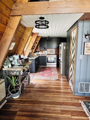 A kitchen with wooden beams, a microwave, stove, and a refrigerator.