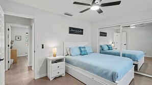 A bedroom with two beds, a ceiling fan, a bedside table with a lamp, and a mirror. - Newly Remodeled Oasis.  Pool, Spa & BBQ Near London Bridge  Sleeps 8 (Lake Havasu City)