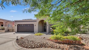 A residential house with a garage, a driveway, and a landscaped garden with rocks and plants. - Newly Remodeled Oasis.  Pool, Spa & BBQ Near London Bridge  Sleeps 8 (Lake Havasu City)