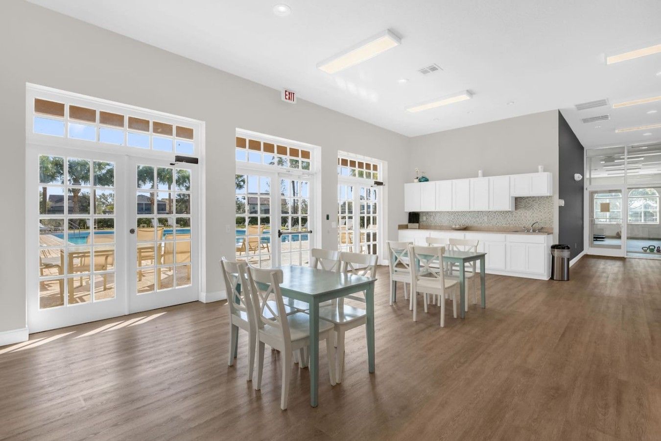 A spacious room with a dining area, kitchen, and large sliding glass doors leading to a pool area.