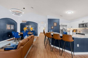 A modern kitchen with white cabinets, a stainless steel refrigerator, and a microwave. - Private Screened Pool | Sleeps 14 | Themed Bunks, Ping Pong & No Rear Neighbors (Davenport)