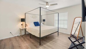 Un lit à baldaquin équipé d’un ventilateur de plafond, de lampes de chevet et d’une fenêtre avec des stores.