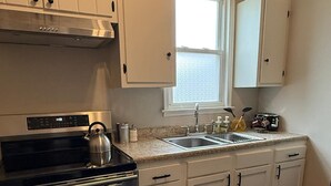A kitchen with white cabinets, a stainless steel range, a window, and a sink. - The Retro Nook - cozy studio near Spooky Nook. (Hamilton)