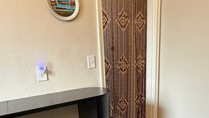 A room with a desk, a stool, a power outlet, and a decorative item on the wall. - The Retro Nook - cozy studio near Spooky Nook. (Hamilton)