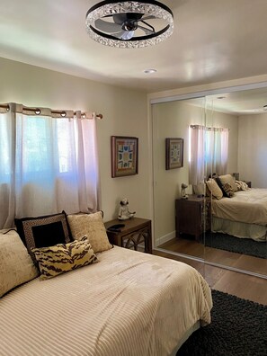 A bedroom with a bed, a nightstand, a mirror, and a ceiling fan. - Upscale, Family Friendly Coastal Retreat.
2 Blocks from So Cal’s, Seal Beach (Seal Beach)