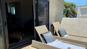 A sunlit outdoor lounge area with wicker furniture and a sliding glass door leading to an interior space. - Upscale, Family Friendly Coastal Retreat.
2 Blocks from So Cal’s, Seal Beach (Seal Beach)