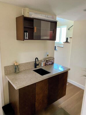 A kitchen with a granite countertop, a black sink, and a wooden cabinet.