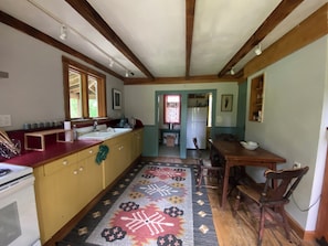 A kitchen with wooden cabinets, a stove, a sink, and a dining area with a table and chairs.