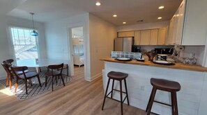Una cocina moderna con armarios blancos, encimera de madera y una zona de comedor con mesa redonda y sillas.