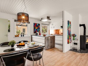 Een moderne keuken met een centraal eiland, een eethoek met een tafel en stoelen, en een zwart fornuis.