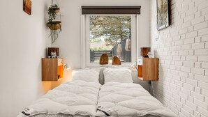 Ein Schlafzimmer mit einem Bett, Nachttischen, einem Fenster mit Blick und einer Ziegelwand.