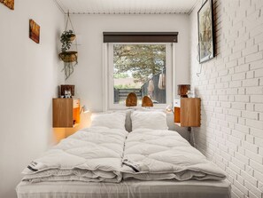 Een slaapkamer met een bed, nachtkastjes, een raam met uitzicht en een bakstenen muur.