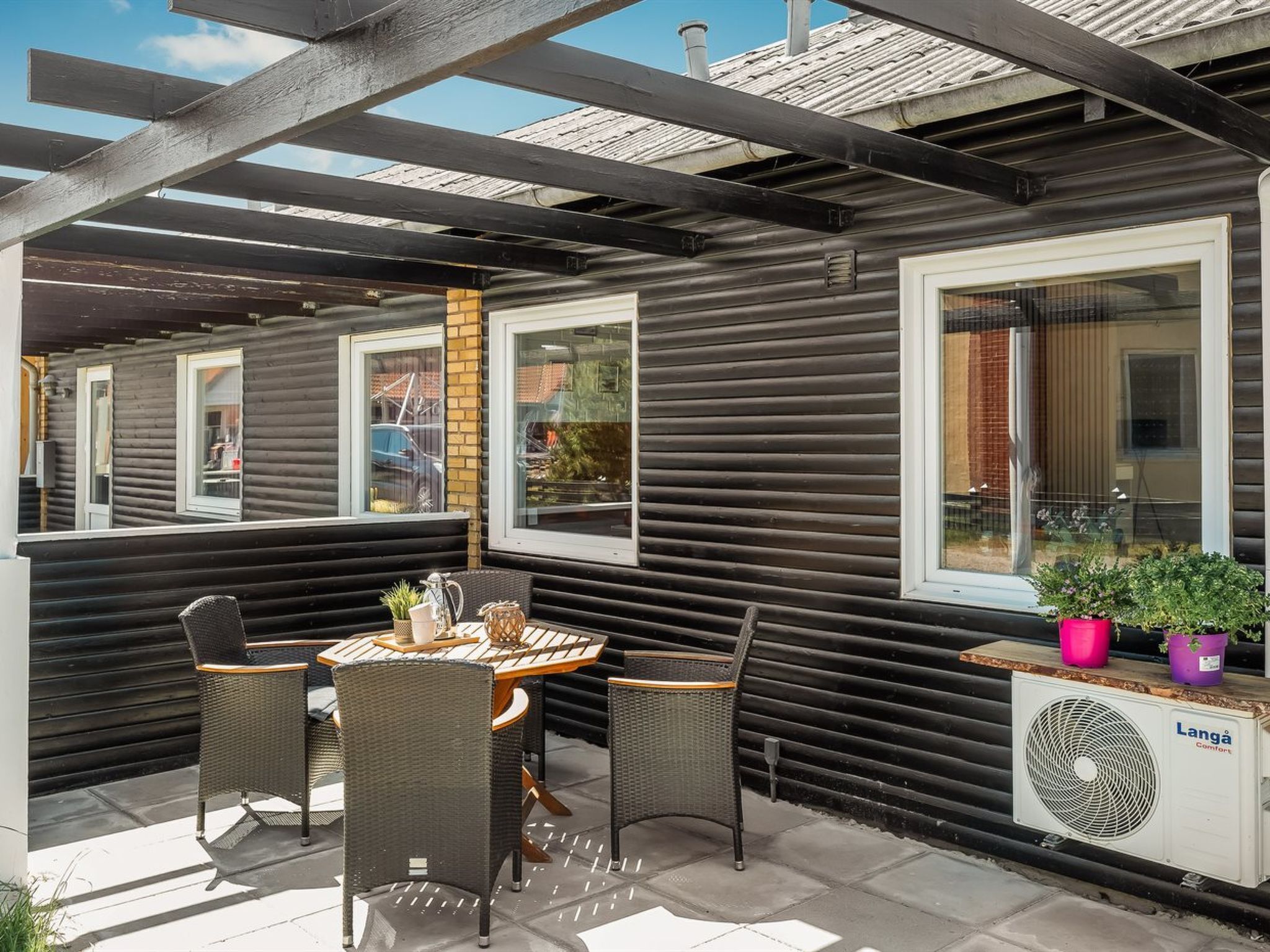Un patio coperto con tavolo e sedie, una finestra vista e un condizionatore Langa Comforts.