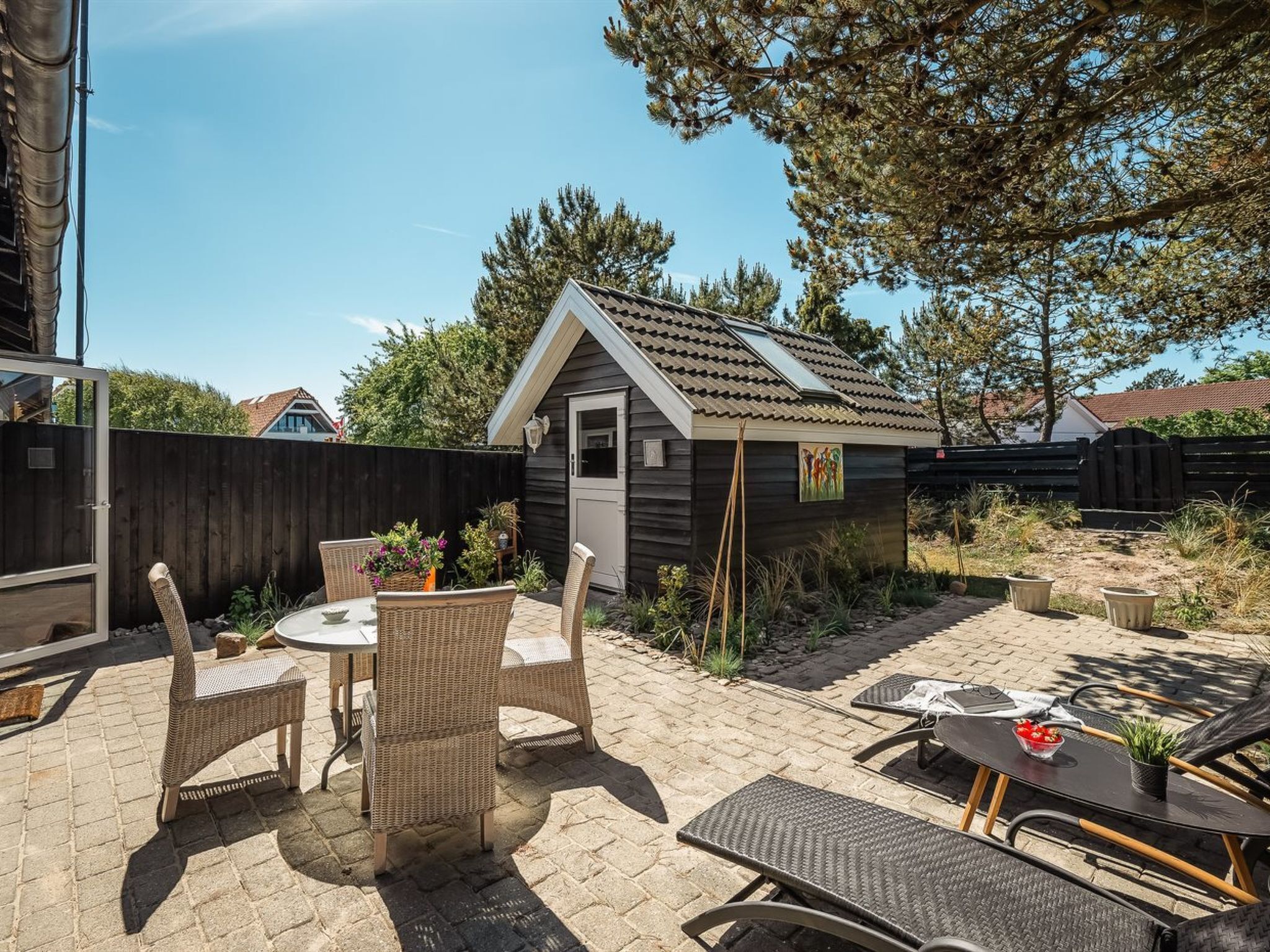 A patio area with wicker furniture, a small shed, and a garden.