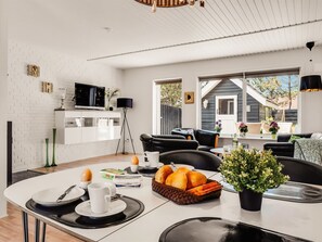 Een moderne keuken met witte kasten, een eethoek met een witte tafel en een zwarte leren bank.