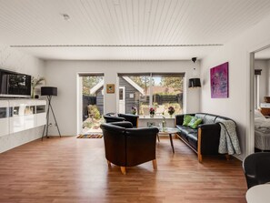 Een moderne woonkamer met een televisie, bank en salontafel.