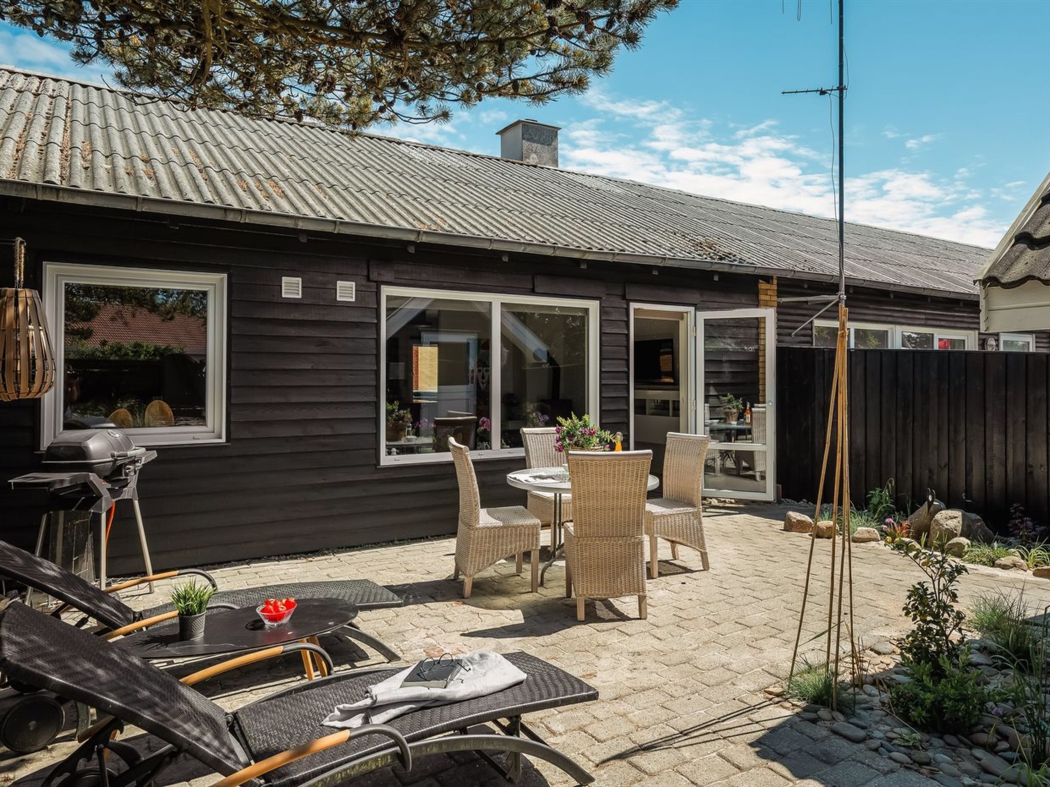 Een huis met een patio, meubilair buiten, een barbecue en uitzicht op de achtertuin.