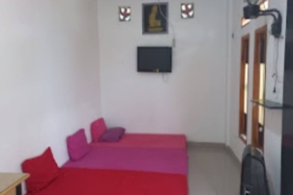 Una habitación pequeña con una cama, un televisor instalado en la pared y una ventana con vistas.