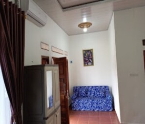 Una habitación con sofá, televisión y puerta.
