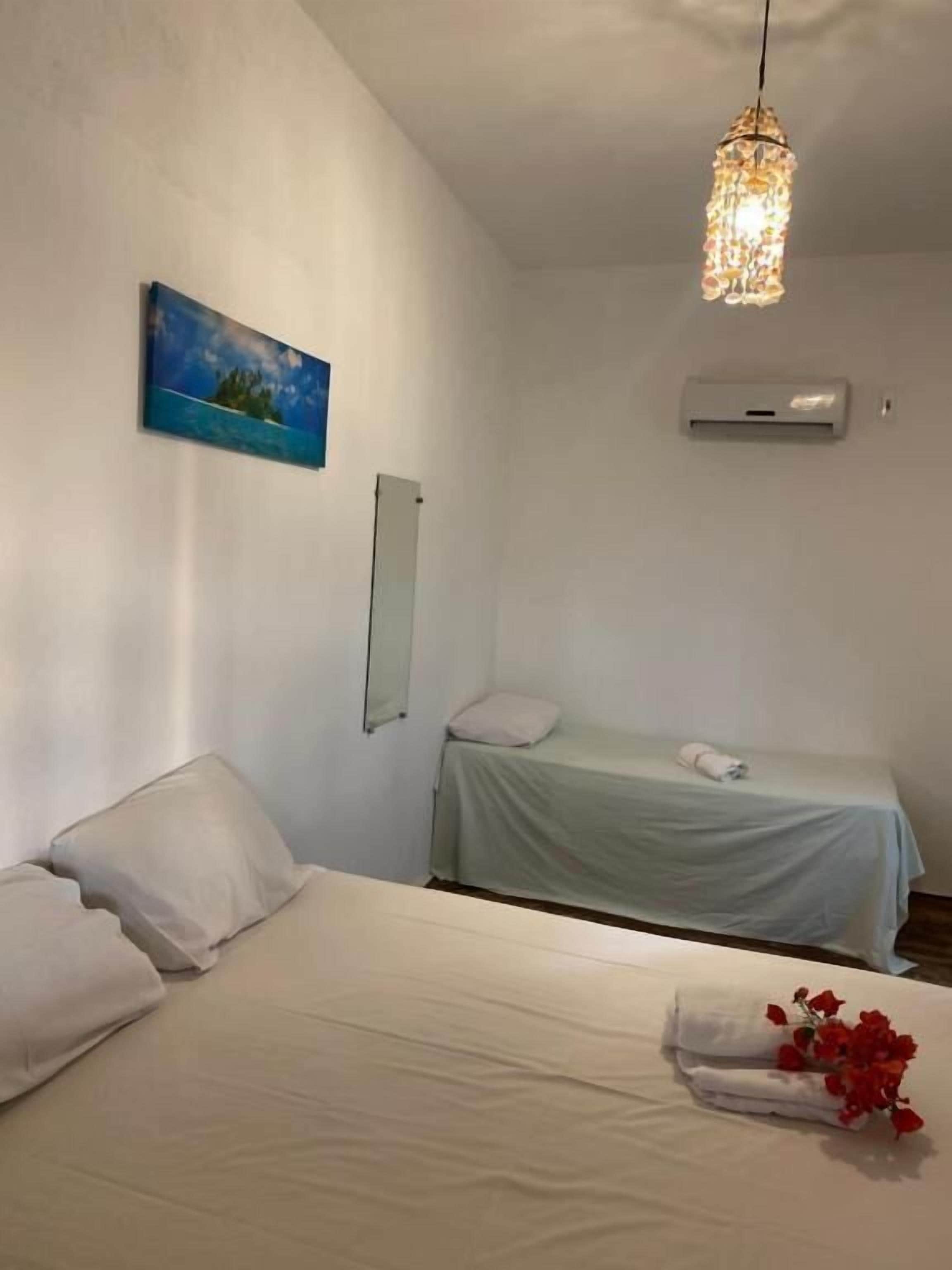 Ein Schlafzimmer mit einem Bett, einem Nachttisch, einer Hängeleuchte, einer Wandklimaanlage und einem Gemälde.