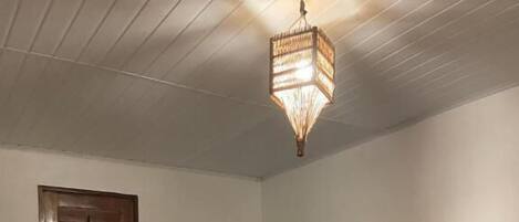 Un dormitorio con cama, cabecero de madera, mesita de noche, espejo y lámpara colgante.