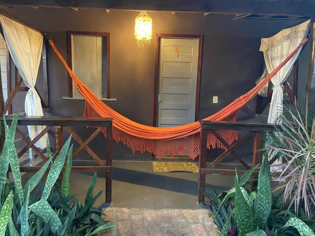 A hammock set up between two wooden structures with a door and a hanging light fixture in the background.