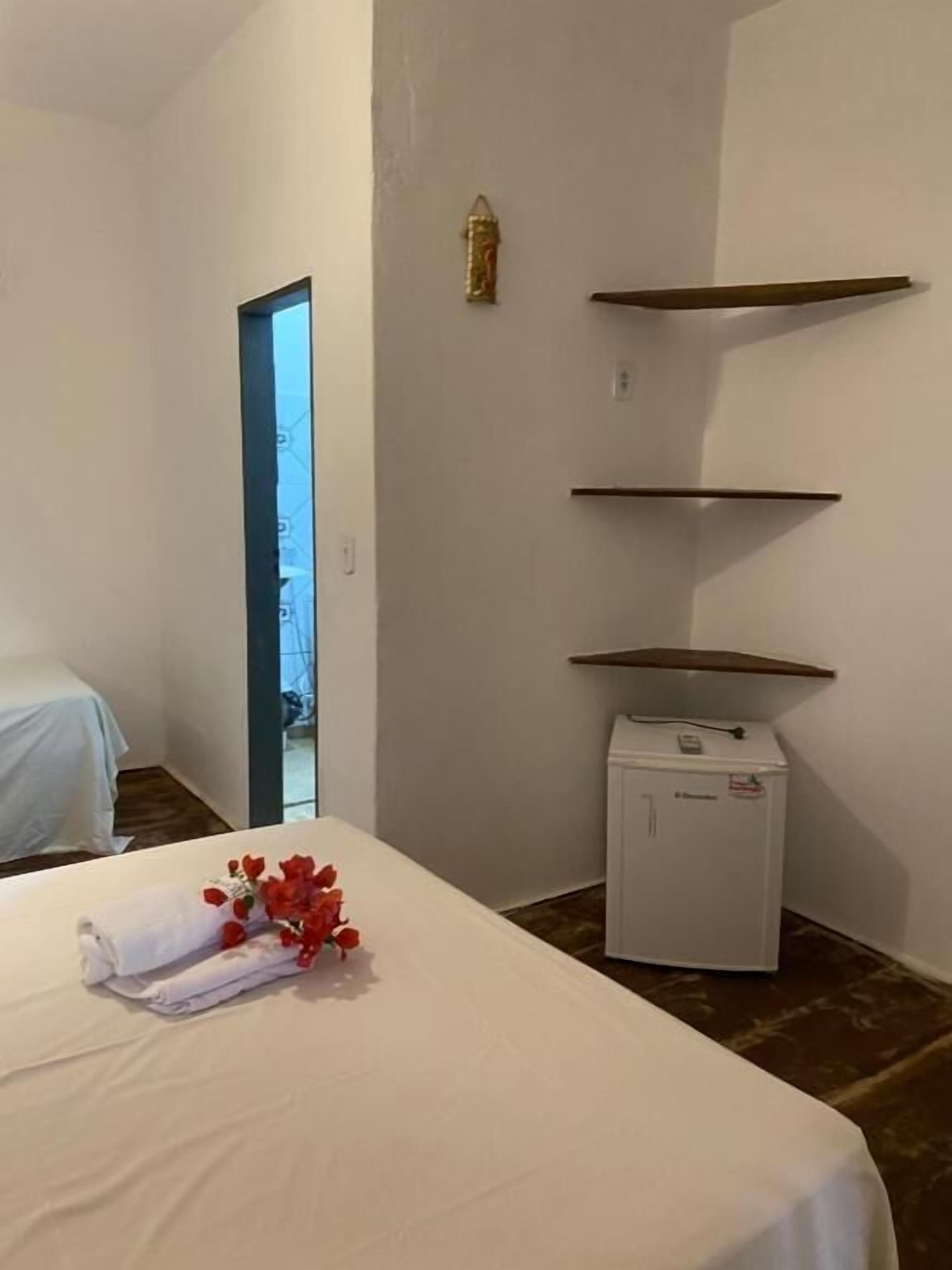 Una habitación de hotel con una cama, un pequeño electrodoméstico blanco y una puerta que da a otra habitación.
