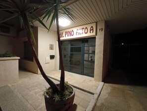 En bygningseingang med et skilt, der viser 'Pinto Alto A', og en potteplante i forgrunden.