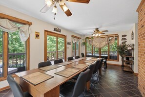 A conference room with a long table, chairs, ceiling fans, and large windows.