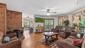 A spacious living room with a fireplace, leather sofas, a wooden coffee table, and a ceiling fan.
