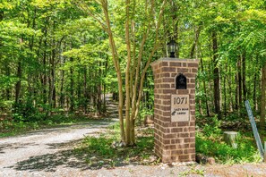 A brick structure with a sign reading '1071 Lazy Bear Lodge' in a forested area.