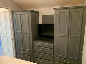 Ein Schlafzimmer mit Kleiderschrank, Fernseher und einer Tür.