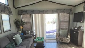 Una sala de estar con un sofá, una mesa de billar, un sillón estampado y un televisor.