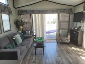 Ein Wohnzimmer mit einer Couch, einem Billardtisch, einem gemusterten Sessel und einem Fernseher.
