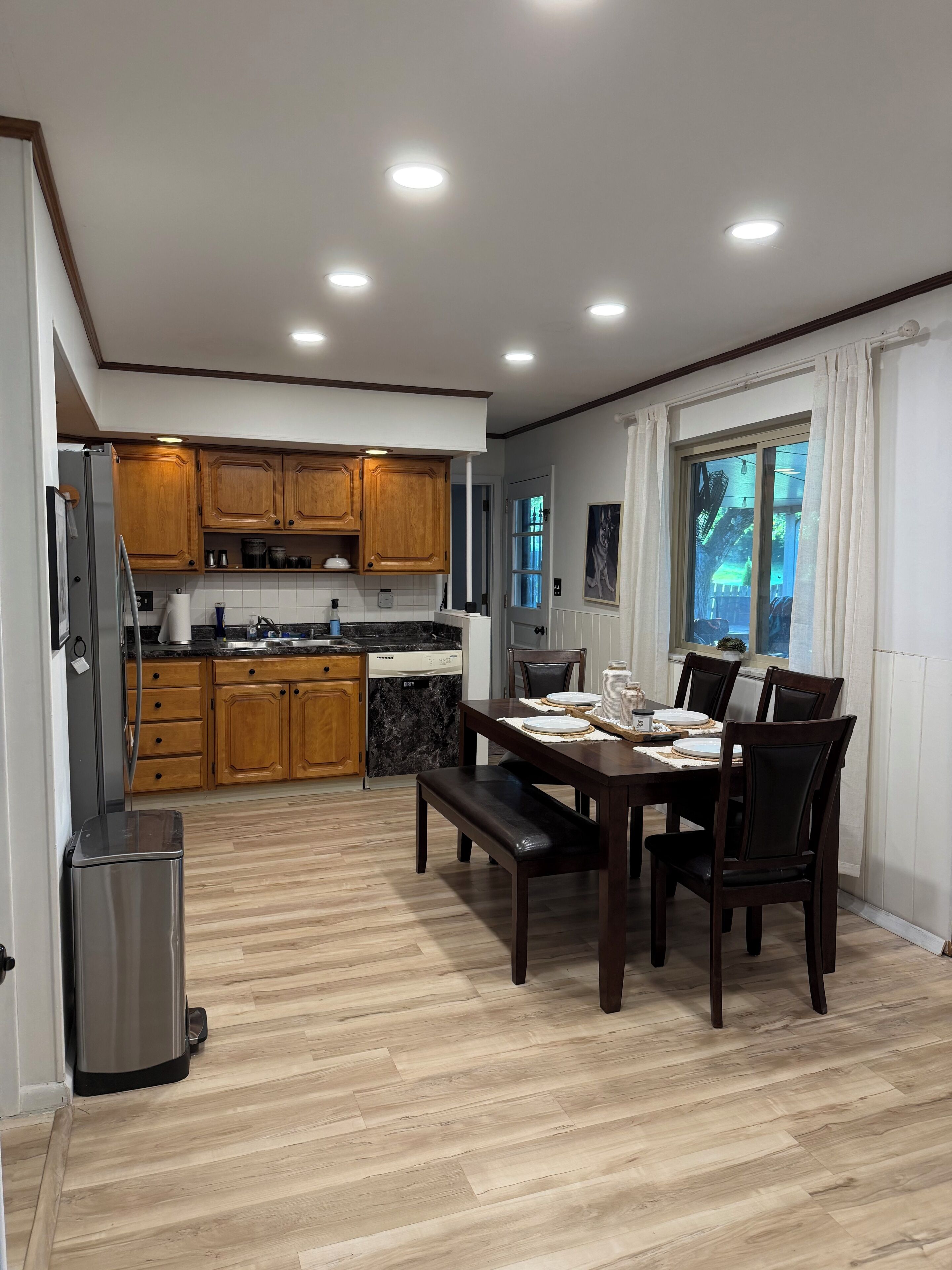 A modern kitchen with wooden cabinets, a dining table with chairs, and a built-in oven.